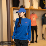 女性モデルがCL by C.ルメールの「LONG TETSU」ブルーを着用。背面には和柄で構成された大きなシルバーの蹄鉄モチーフと、日の丸をイメージした赤い円形デザインを配置。日本製ロングスリーブTシャツとブルーのキャップを合わせた、競馬と日本文化を融合したスタイリング。