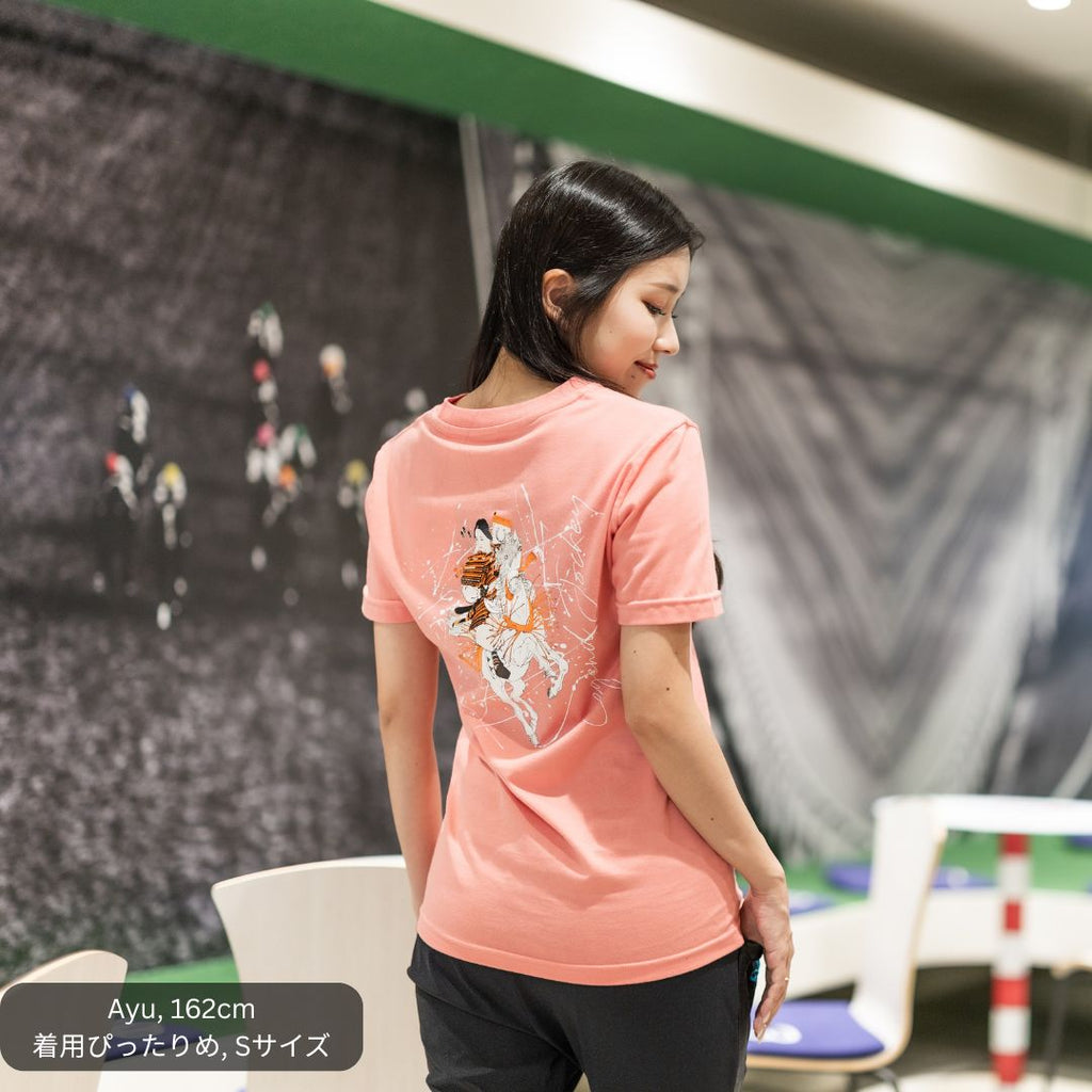 女性モデルがCL by C.ルメールの「LEGEND JOCKEY III」ピンクを着用。背面には日本の女性武将・巴御前（ともえごぜん）をモチーフにしたアートワークを大胆にプリント。馬上で戦う姿を現代的なグラフィックで表現した、日本製コットン100％の半袖Tシャツ。